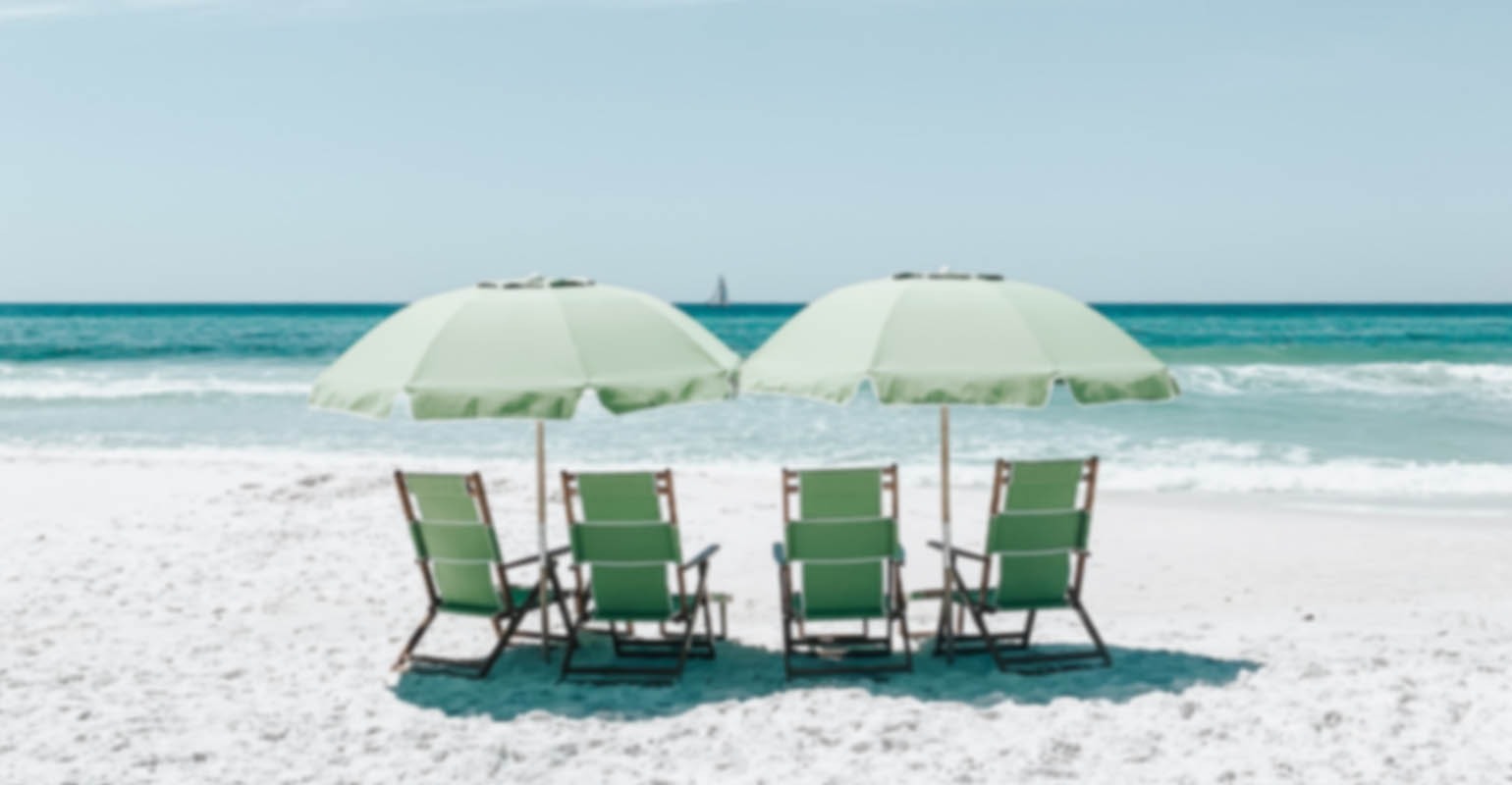 A blurry photo of green chairs under umbrellas on beach sand